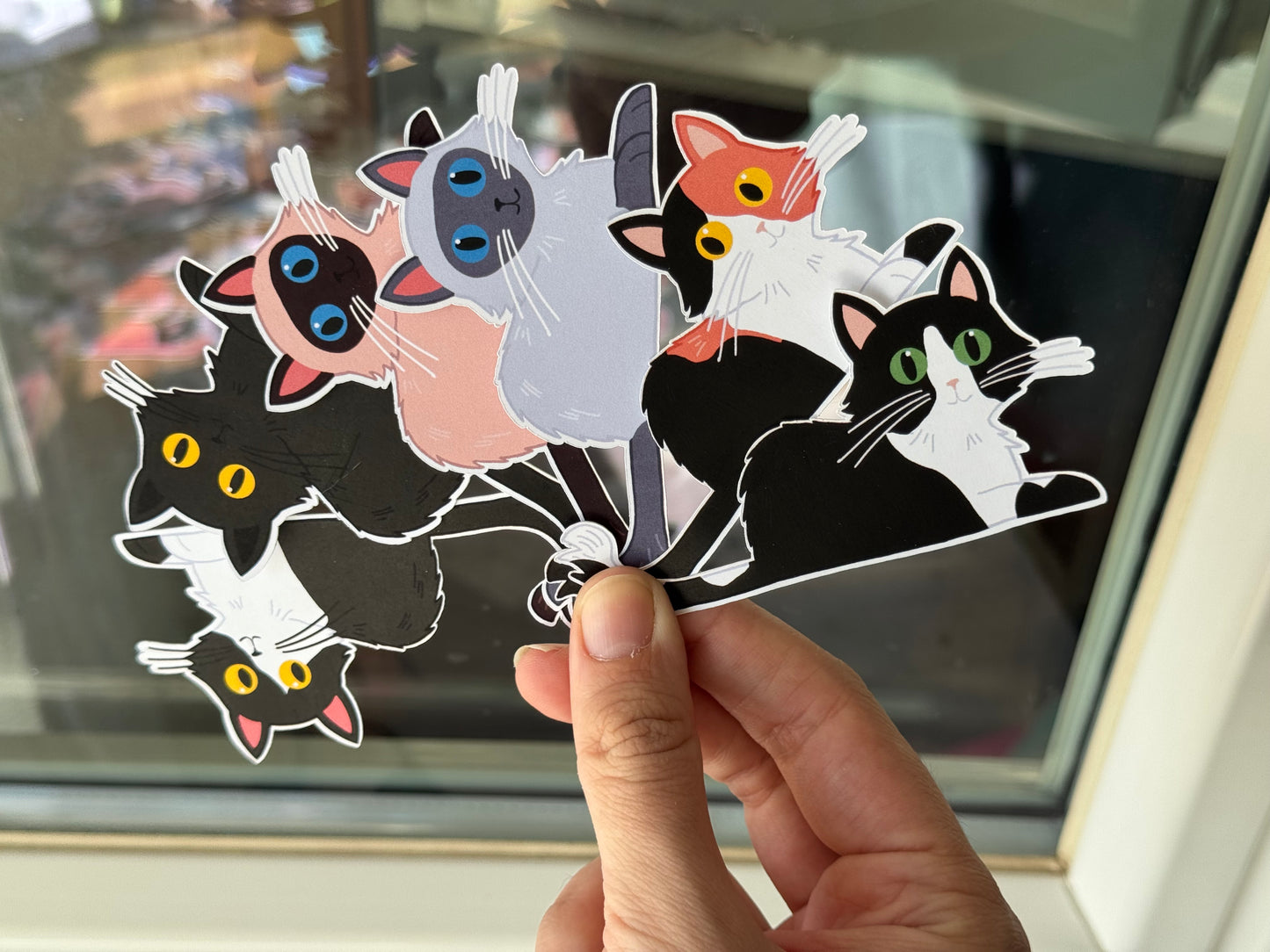 Hand holding a set of colorful long hair cat-shaped stickers 